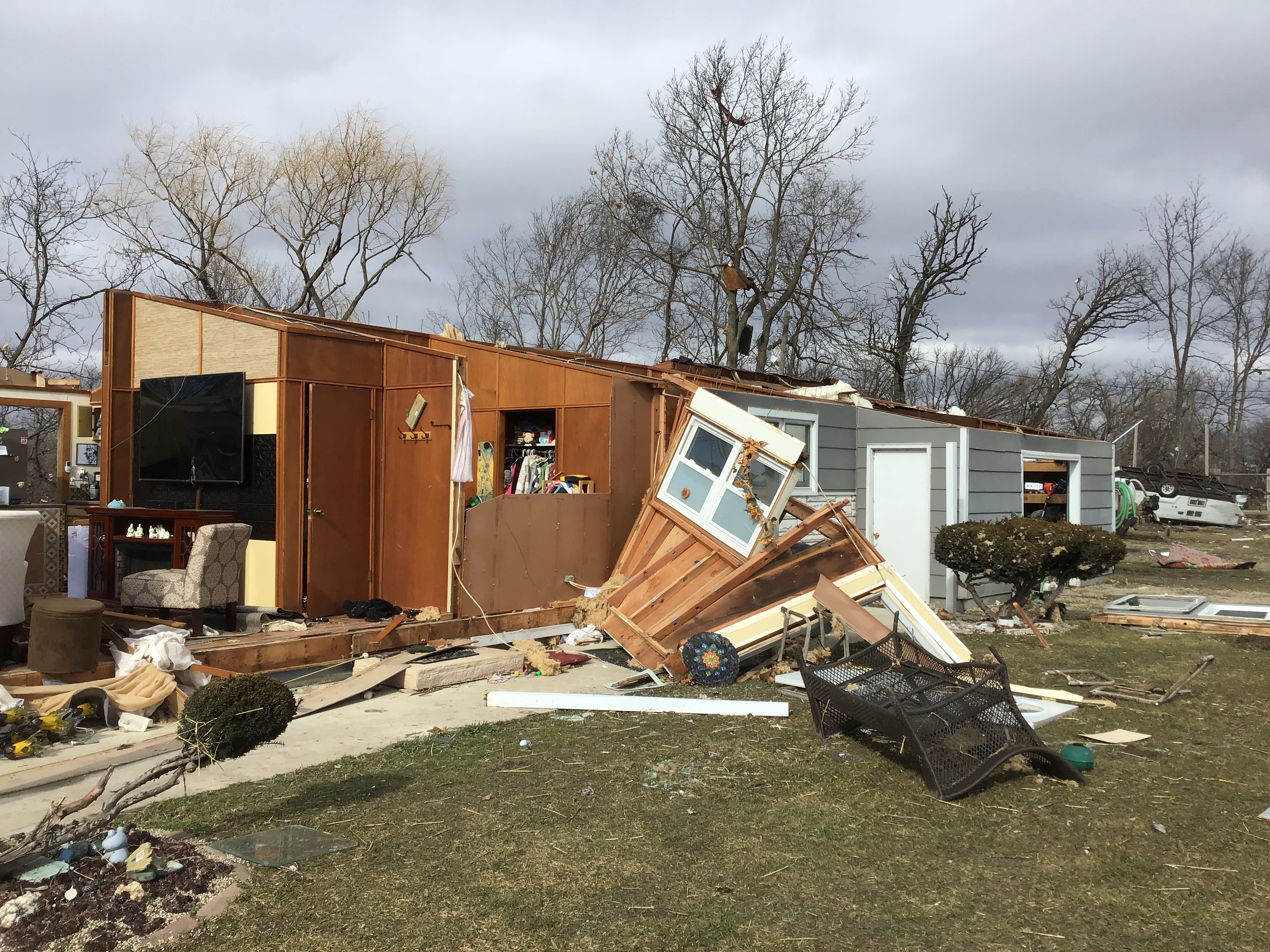 Storm damage to home, debris lofted into trees, trailer rolled