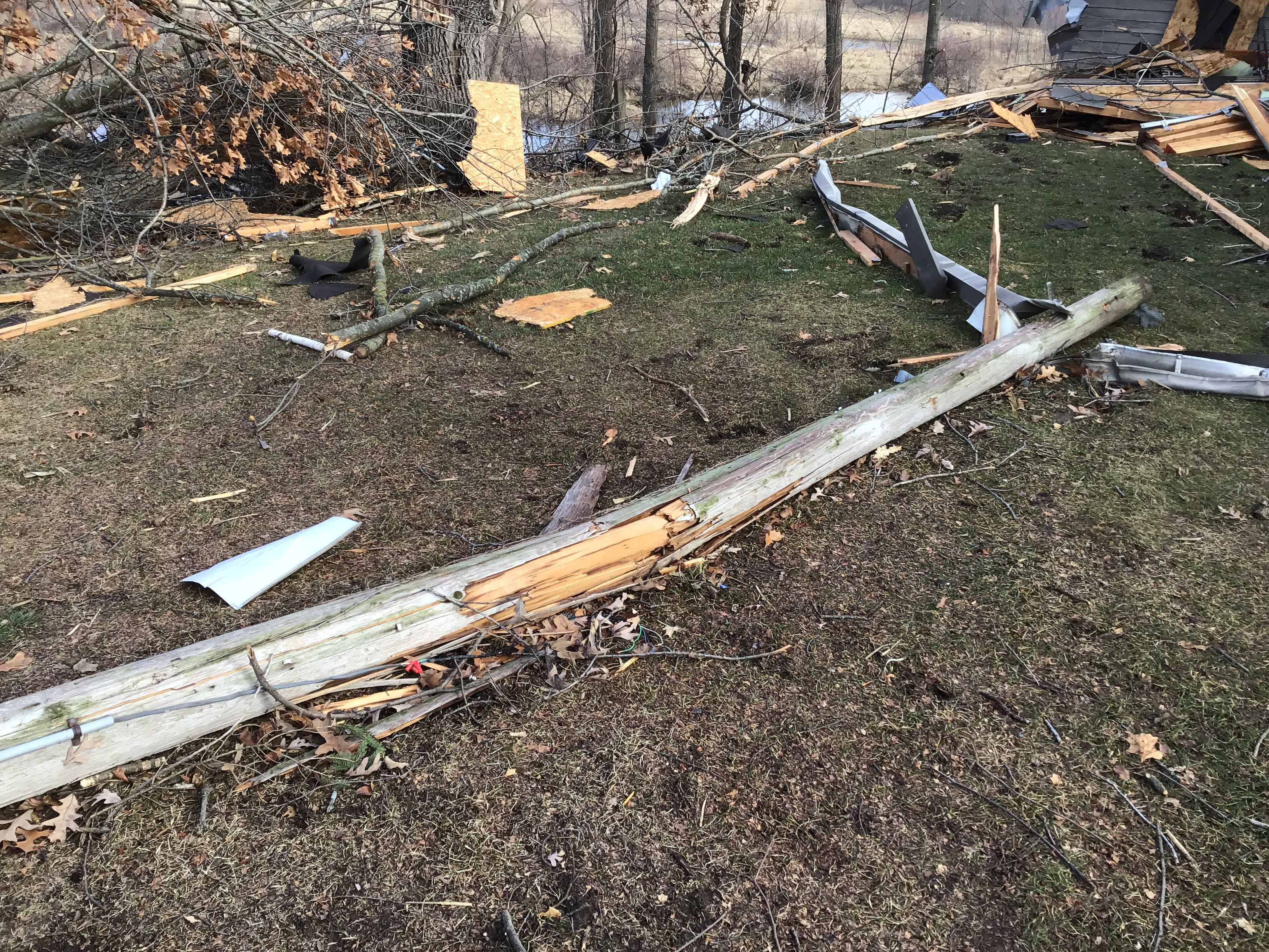 Wooden pole on ground and debris across yard