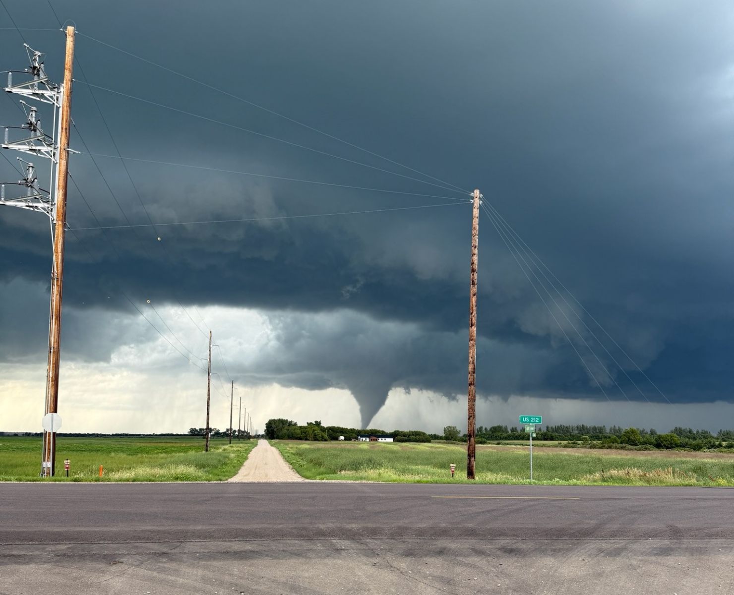 image of a tornado on the horizon of a field behind powerlines