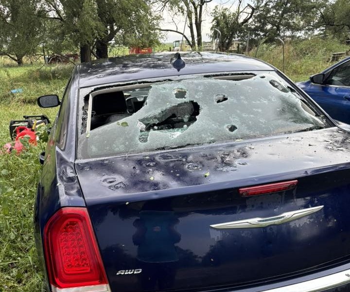 Car's back windshield with massive holes in it from hail stones