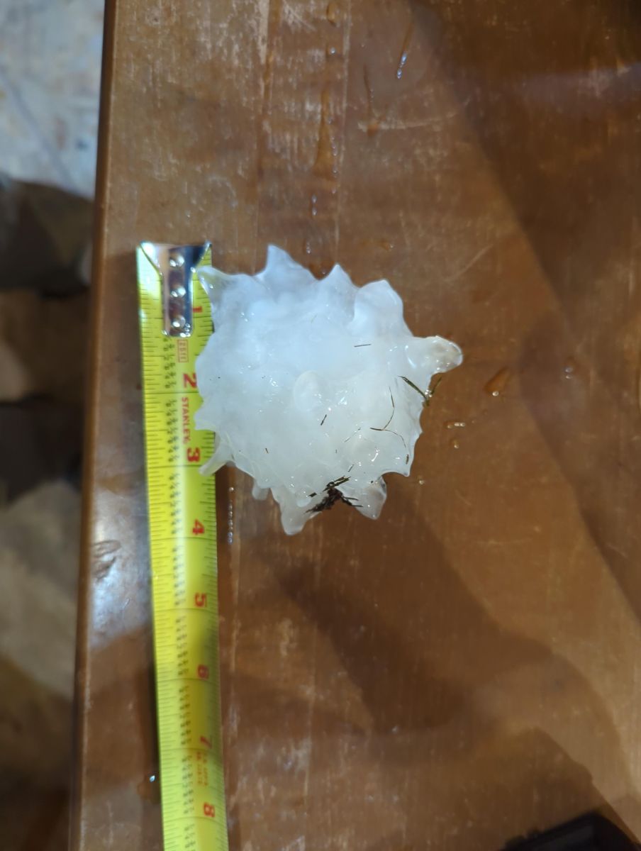 Hail stone a little larger than 3.5 inches next to tape measure