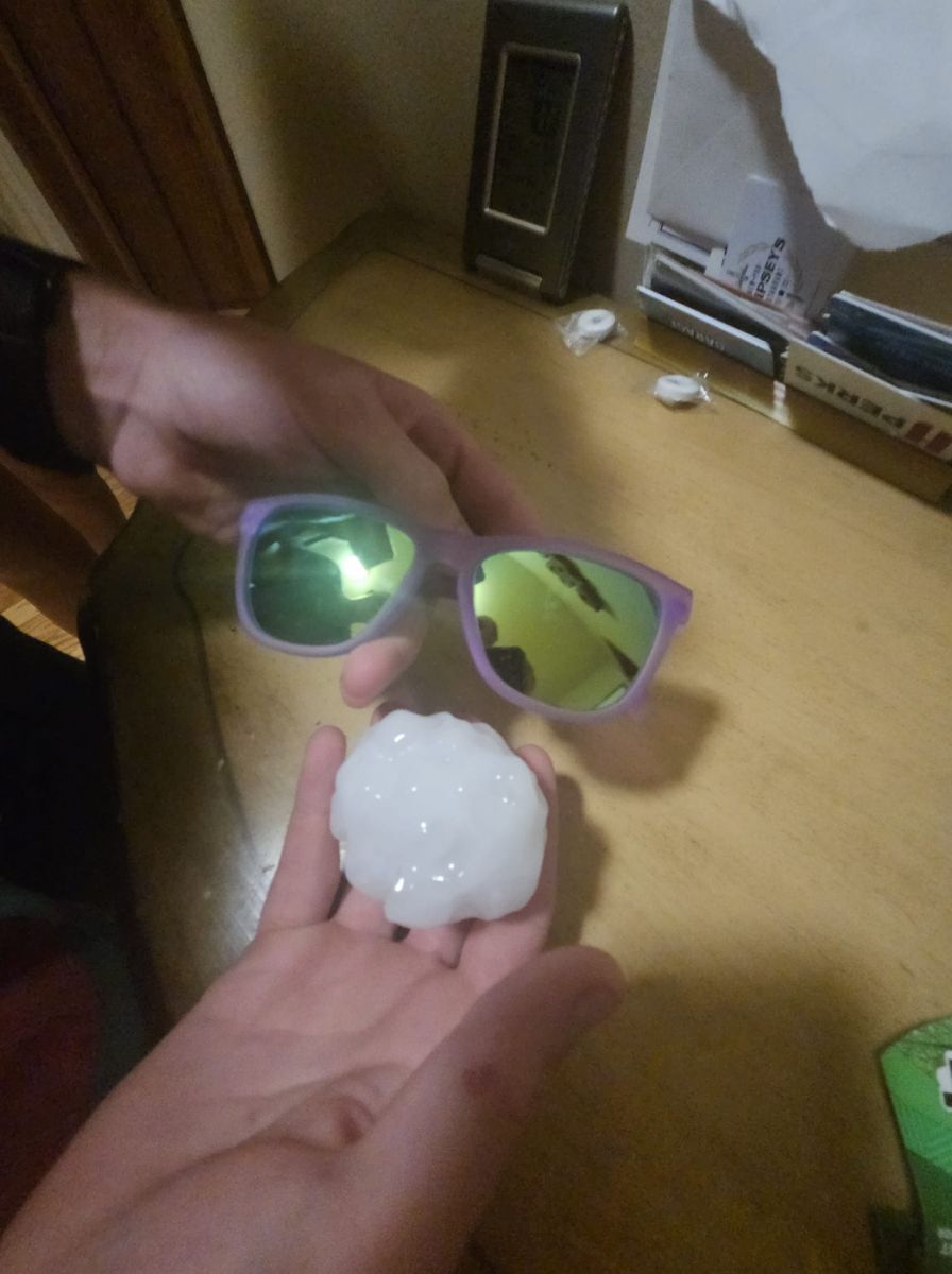 Image of a hail stone next to a pair of sunglasses, with the stone bigger than one of the lenses.
