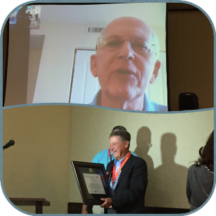 Dr. Neil Frank accepting the Dr. Robert and Joanne Simpson Award at the National Tropical Weather Conference; Max Mayfield assists in the presentation via Skype.