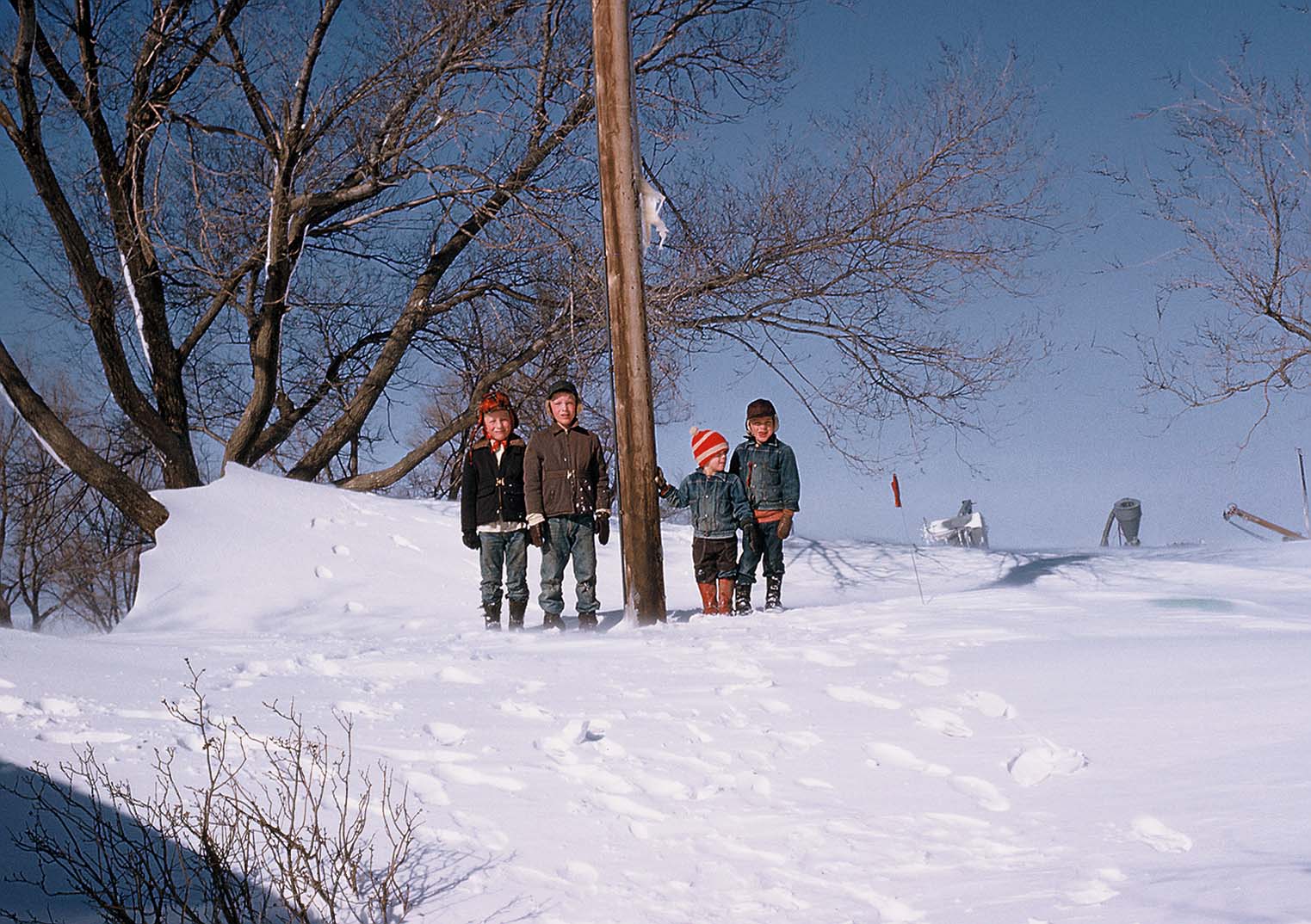 Ed, Joe, Roy and Leo Gerard standing on a snow drift over the car.  There’s a mitten on the antenna.  Don Gerard farm.  19NW Syracuse.