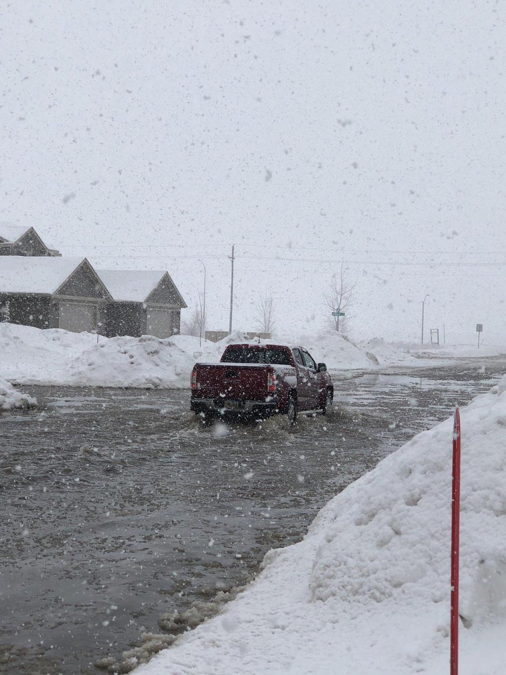 Snow falling into flooded street in southeast Sioux Falls