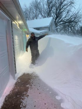 6 foot plus man standing next to a drift up to his head.