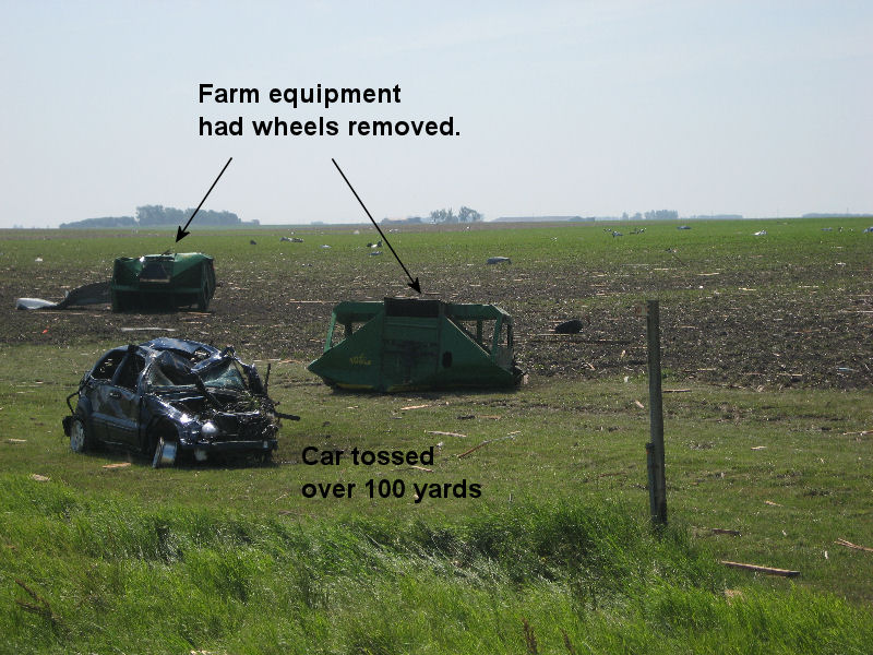 Picture of a car and farm equipment thrown into a field.