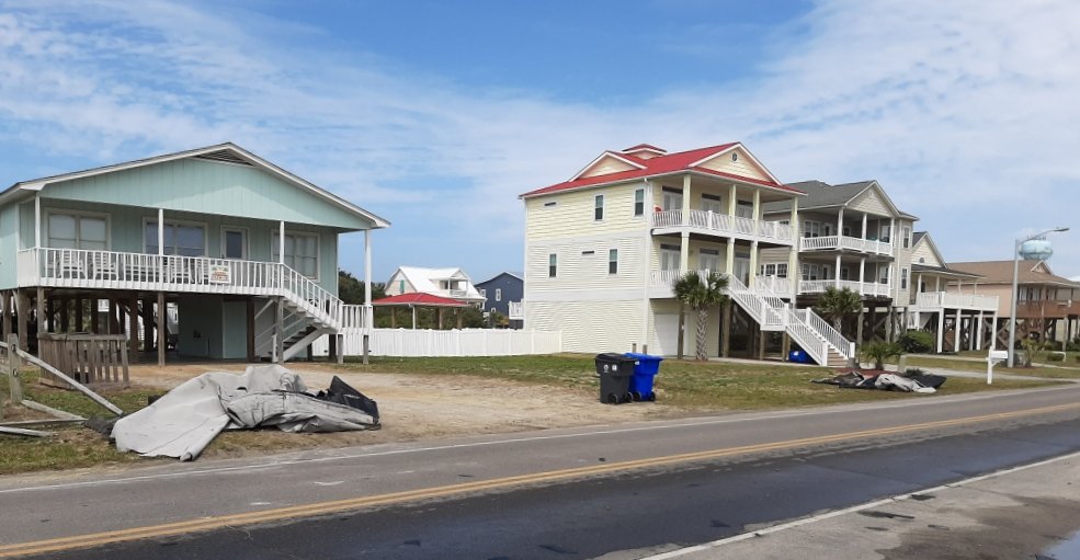 Debris from the Oak Island tornado sits in front of two homes along West Beach Drive in this photo from the afternoon of April 13, 2020