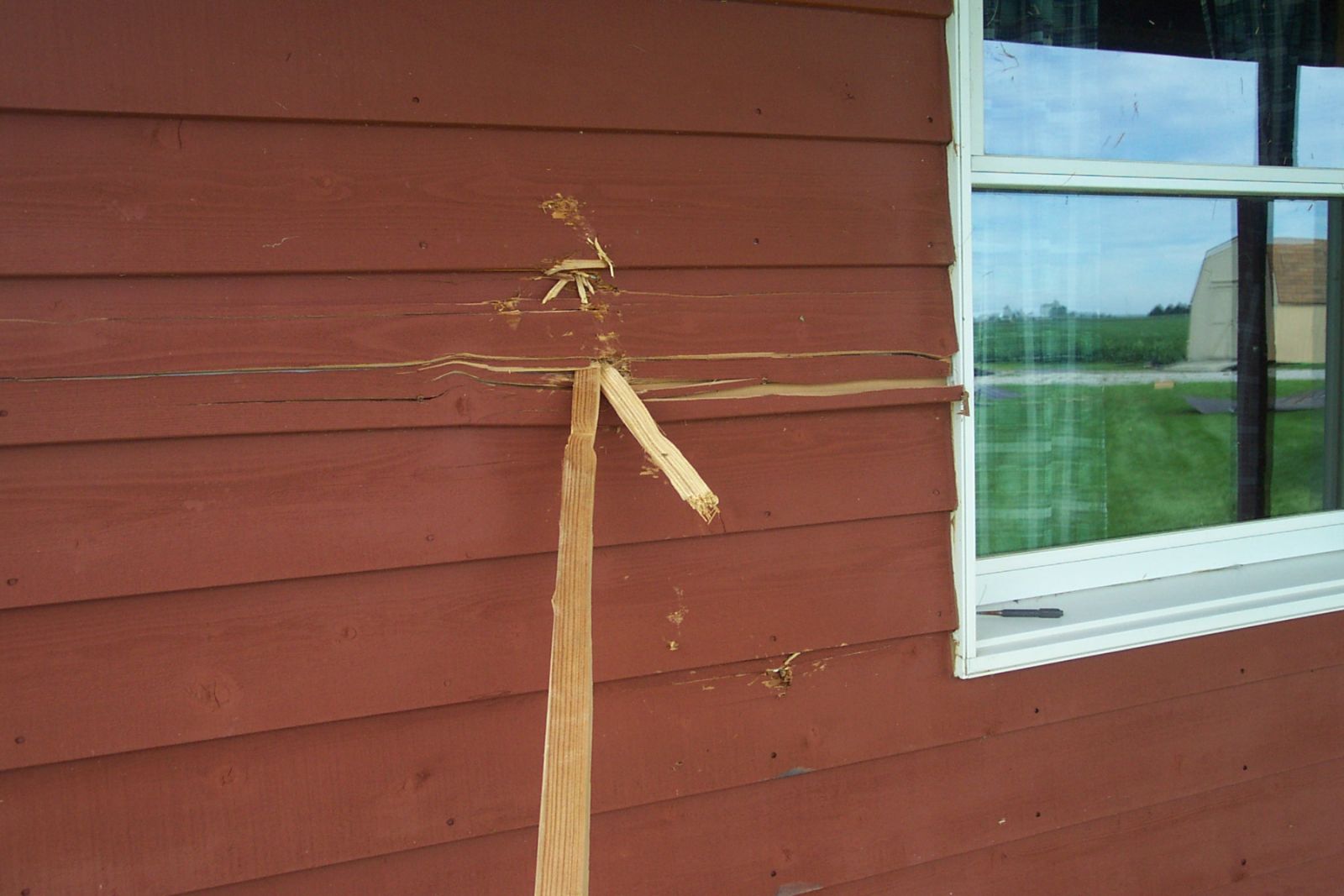A piece of wood from the barn acted like a projectile and embedded into the wall of this house. Production of small projectiles is a sign of F2 wind speeds.