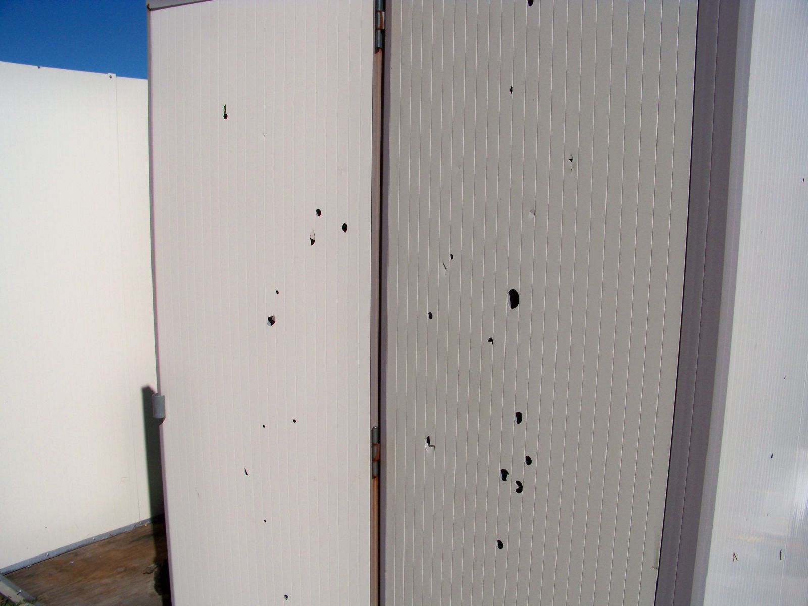 Flying derbis create numerous small holes in this storage shed.