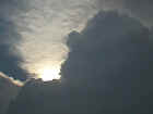 Sun partially obscured by towering cumulus clouds gives the appearance of a
