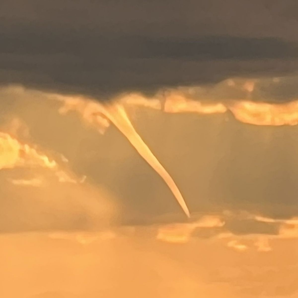 Waterspout at sunset with a white condensation cloud or funnel