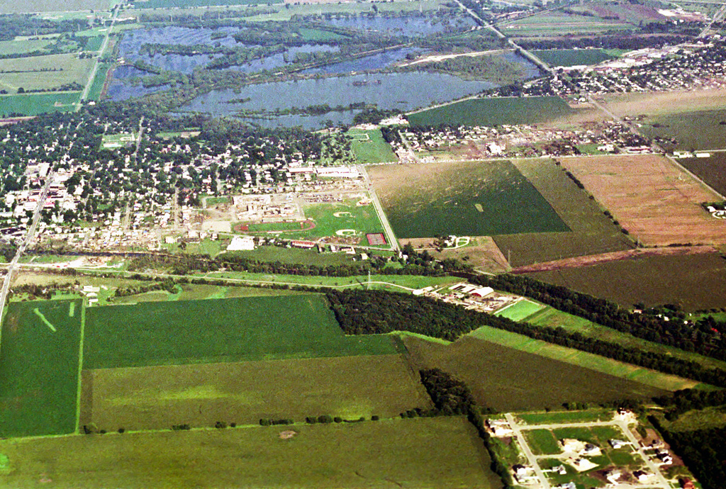 Photo showing damage path of 1990 Plainfield tornado from an airplane. Damage to buildings and vegetation is evident, which creates a clear path from near the foreground to the background. Photo vantage is from just west of Plainfield looking east-southeastward.