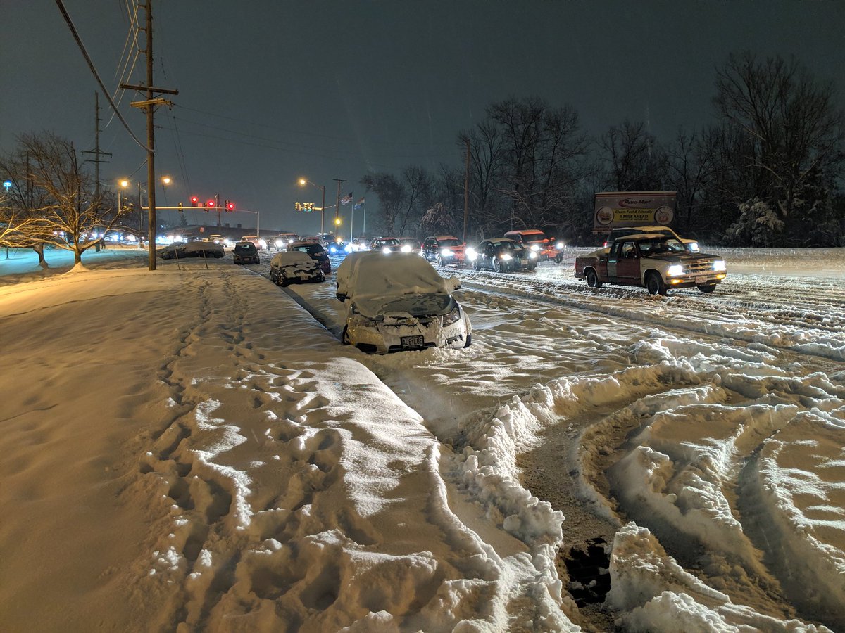 Photo of slow traffic due to snow covering Tesson Ferry Road about two miles south of St. Anthony's Hospital. Also, shows abandoned vehicles from earlier accidents.