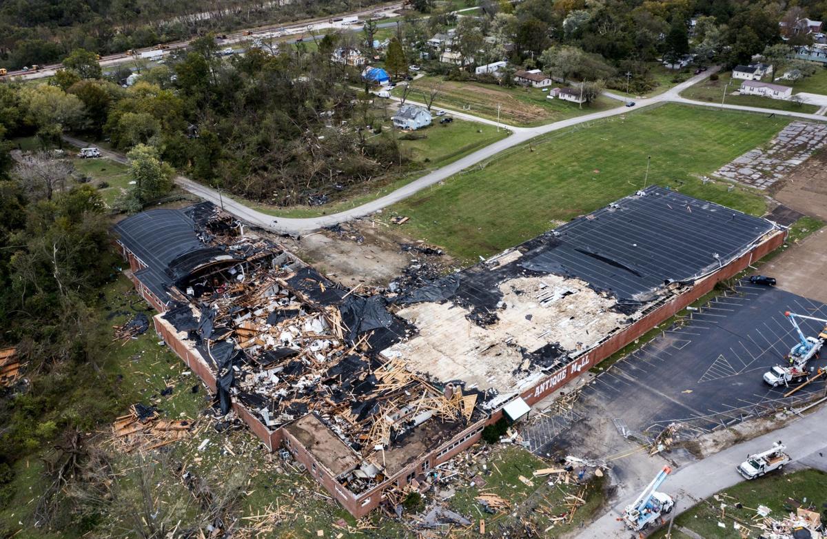 An areal shot of a large, L-shaped Antique Mall. Large sections of the roof have been destroyed and debris from the roof and contents of the building have been scattered across the property.
