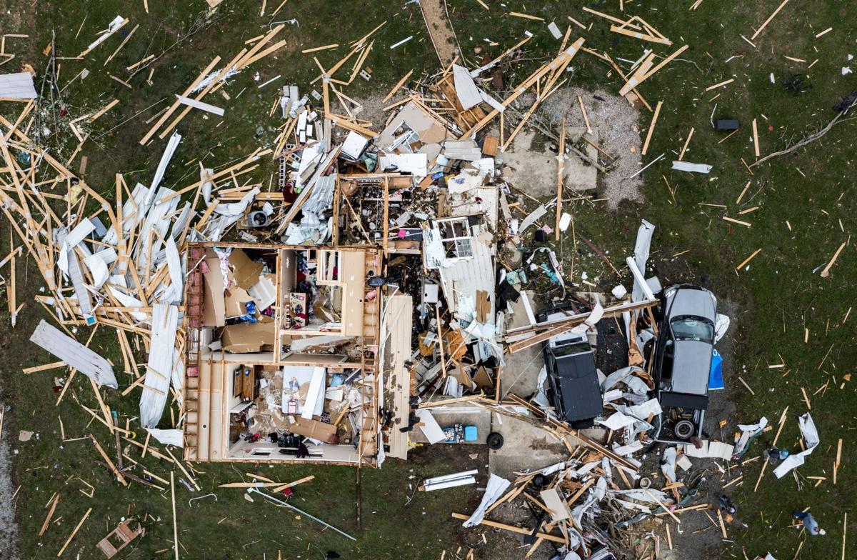 An areal shot of a home damaged by a tornado, the house is open from the top and debris is scattered around the immediate area.