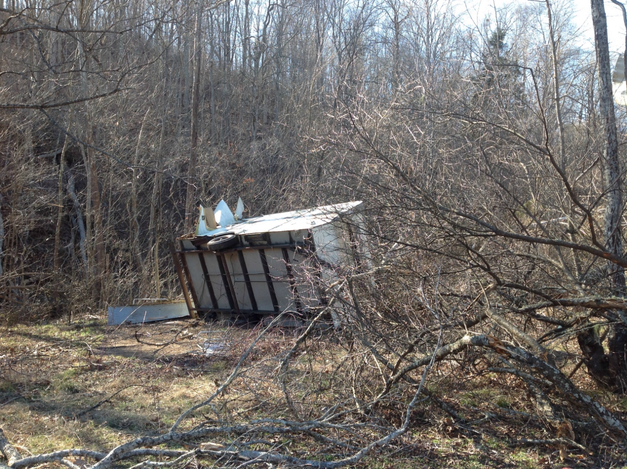 Photo of small mobile home tipped over. glass and curtains sucked out on Horse Shoe Ranch Road.