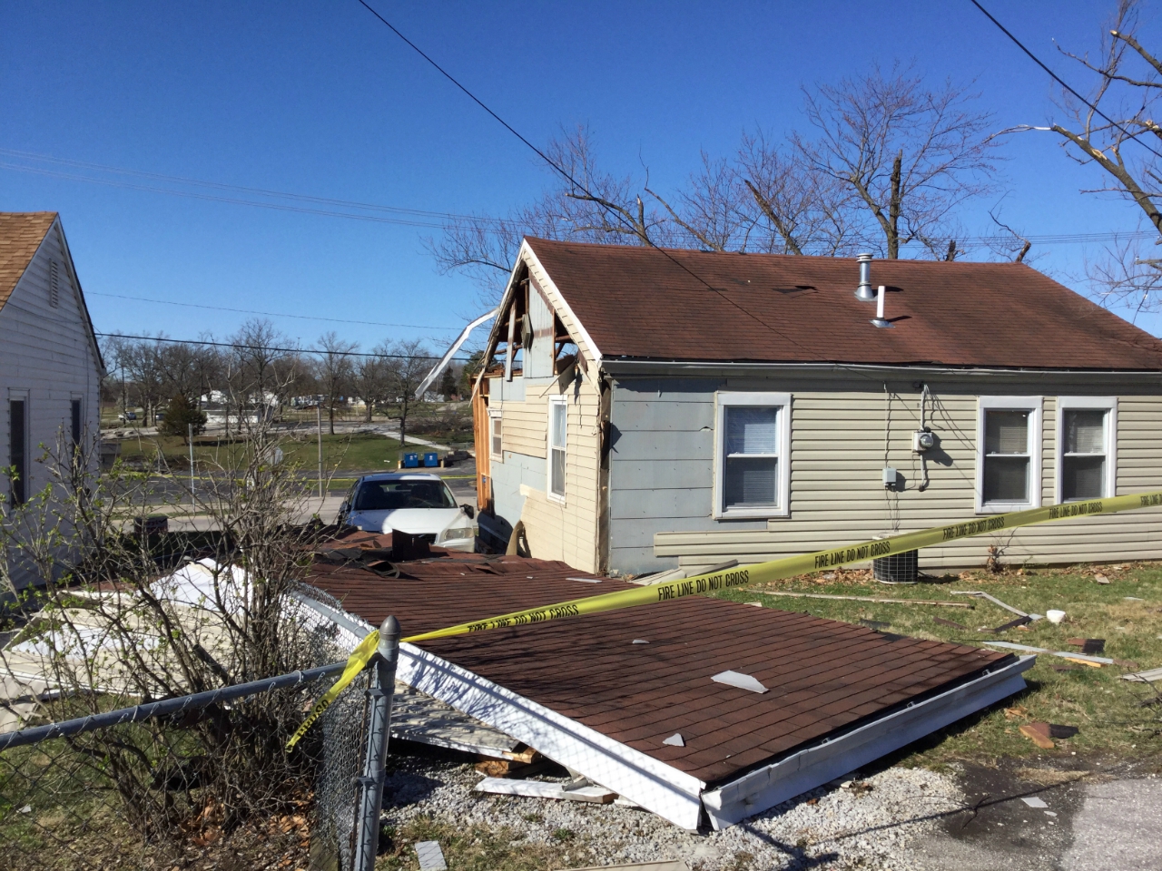 Photo of collapsed car port and damage to roof and wall of house on Circle Drive.