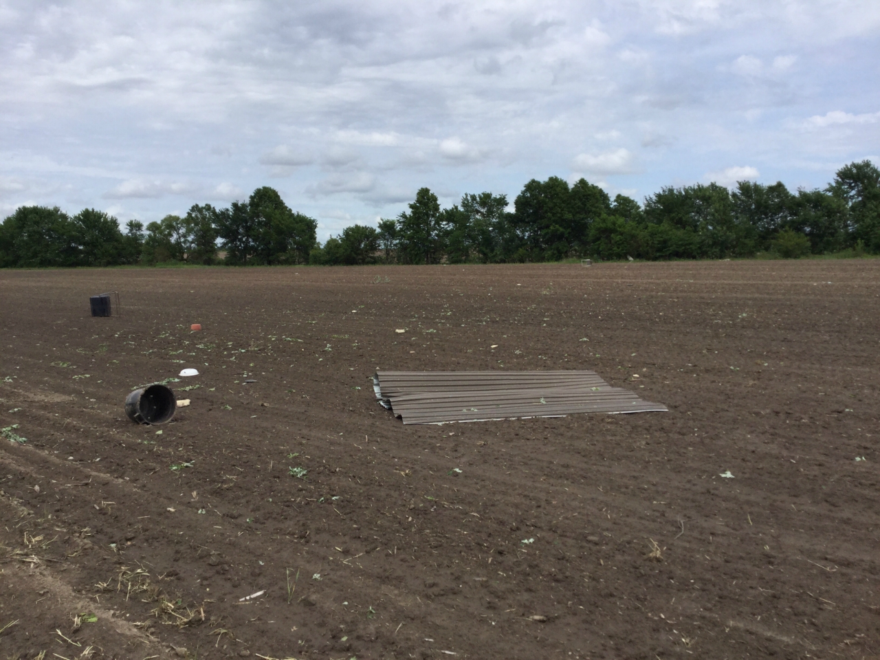 Photo of debris spread across farm field. Some of the debris was from MODOT roofing and garage doors on south side of I-70, with debris evident into the tree line.
