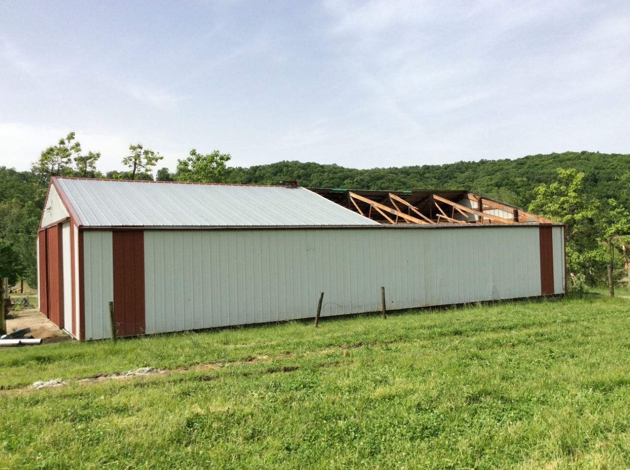 Photo of damage to a portion of the roof of a machine shed.