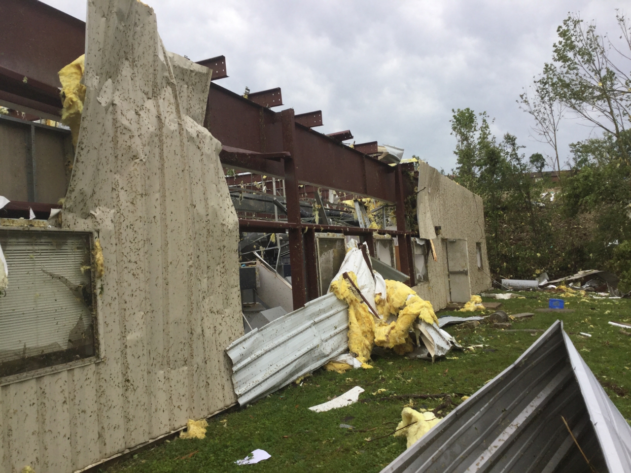Photo of a small office building that had the exterior metal sheeting peeled off and some interior walls blown down.