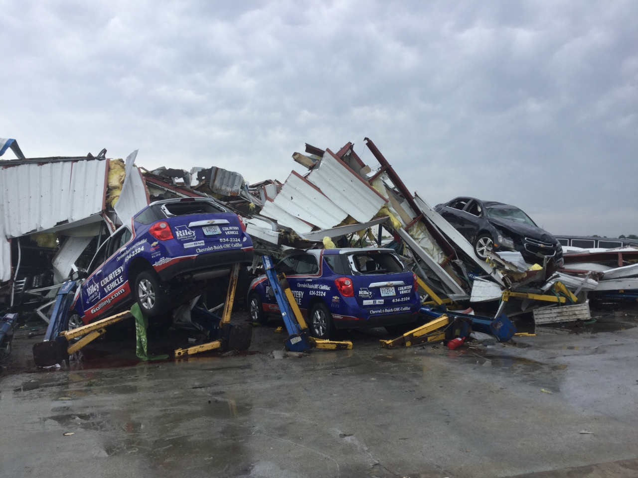 Photo of an automobile service building that collapsed and cars were tossed into the debris.