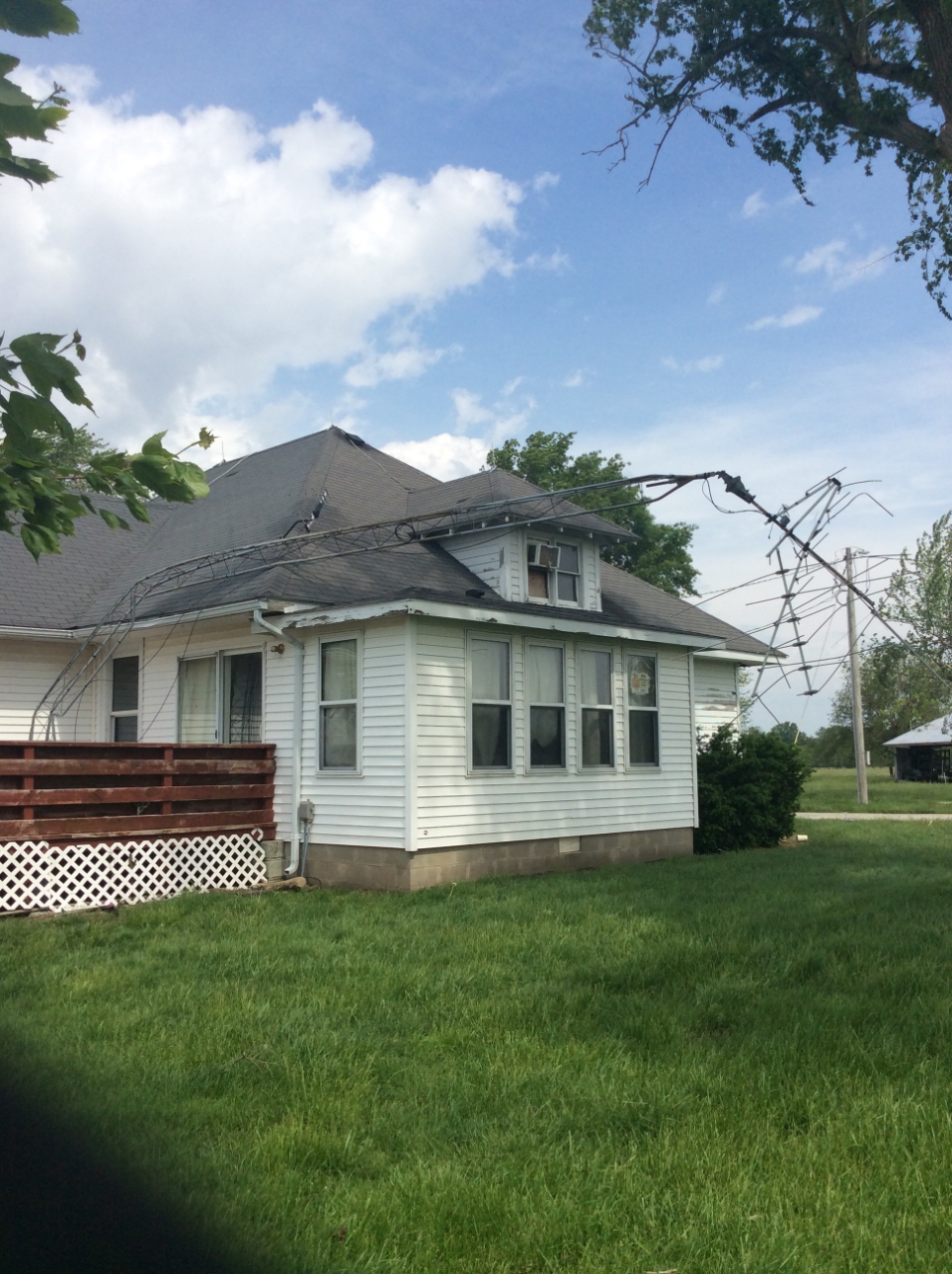 Photo of home radio tower bent over onto roof of house.