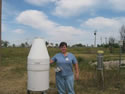 cooperative observer at Hope New Mexico standing beside a rain gauge