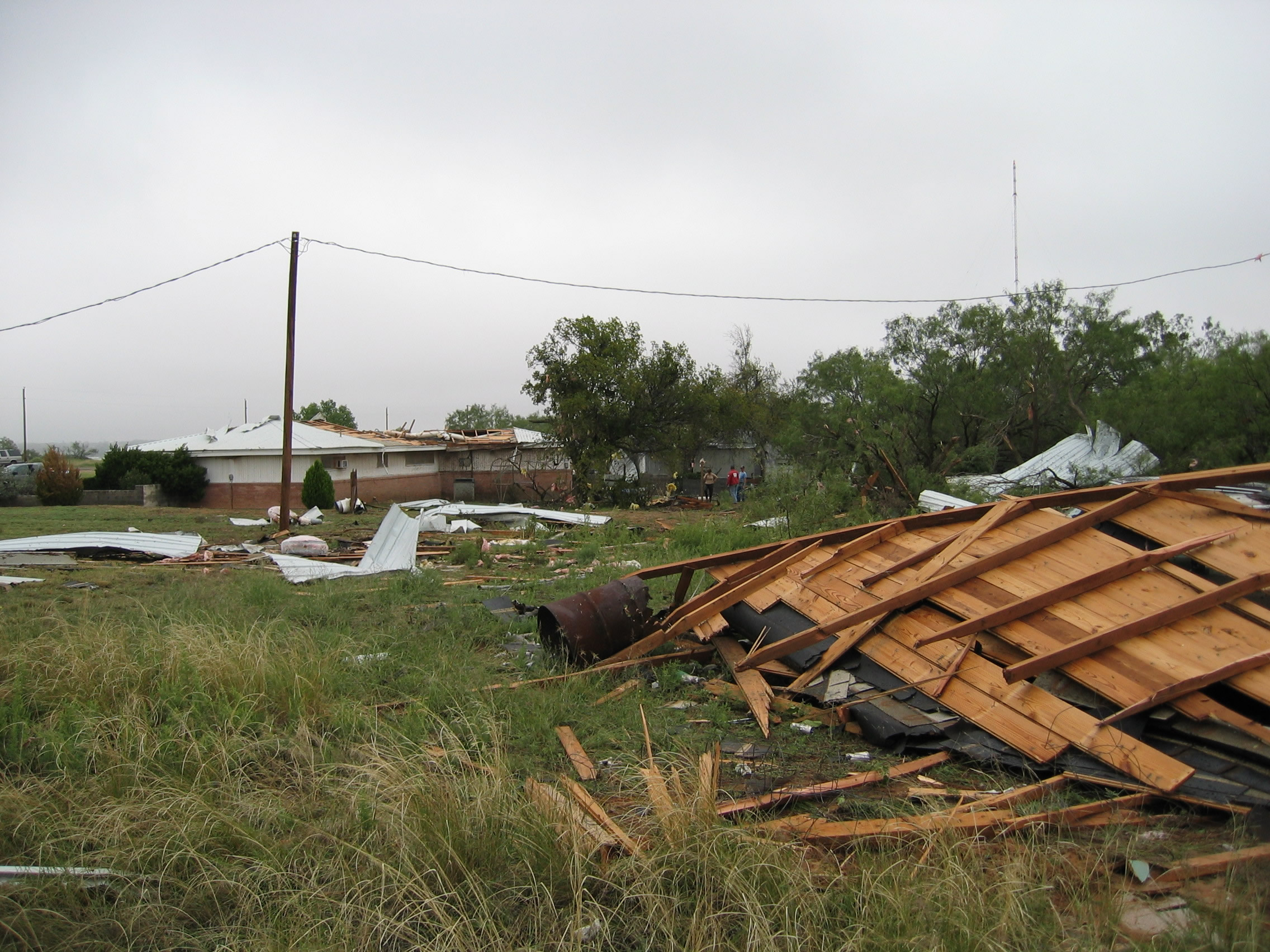 Third photo of house sustaining F1 tornado damage showing more roof blown a significant distance."