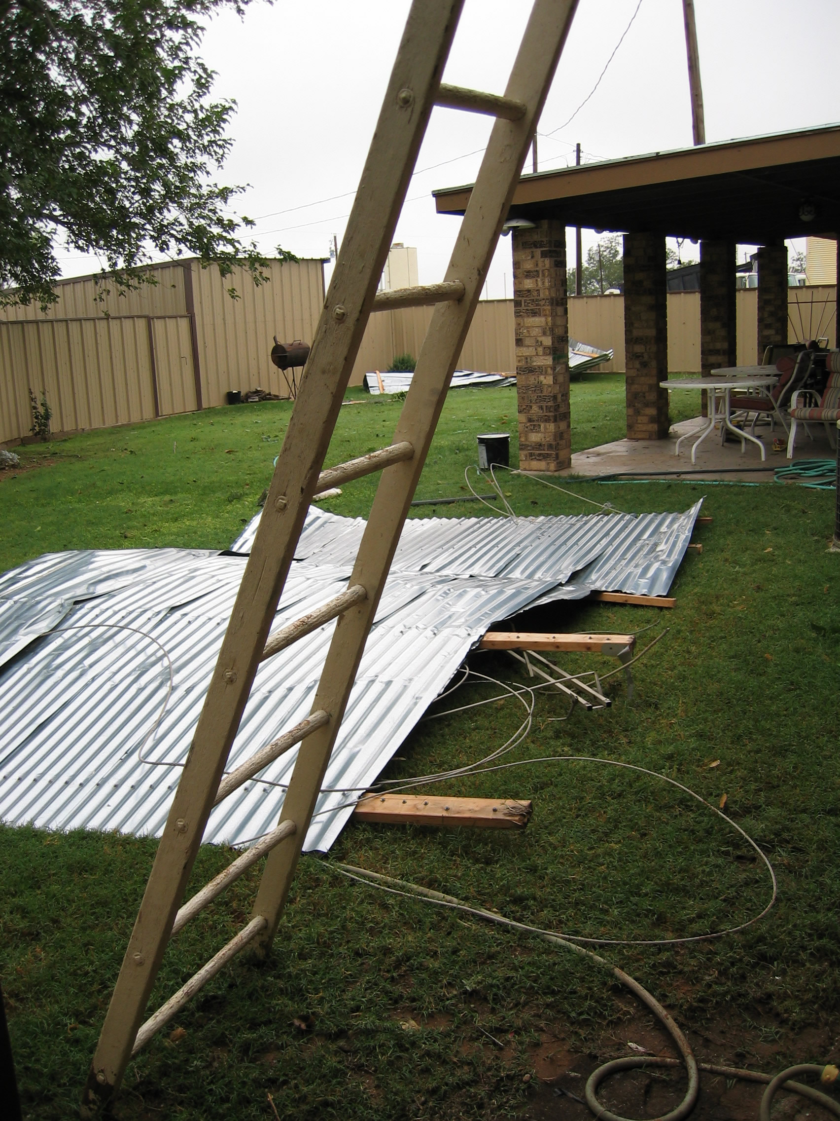 Photo of backyard of an undamaged house with debris blown from the first house, two lots east.