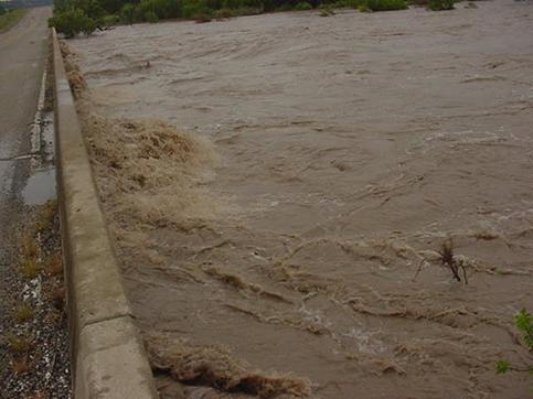 Flood waters nearly reaching the top of a bridge