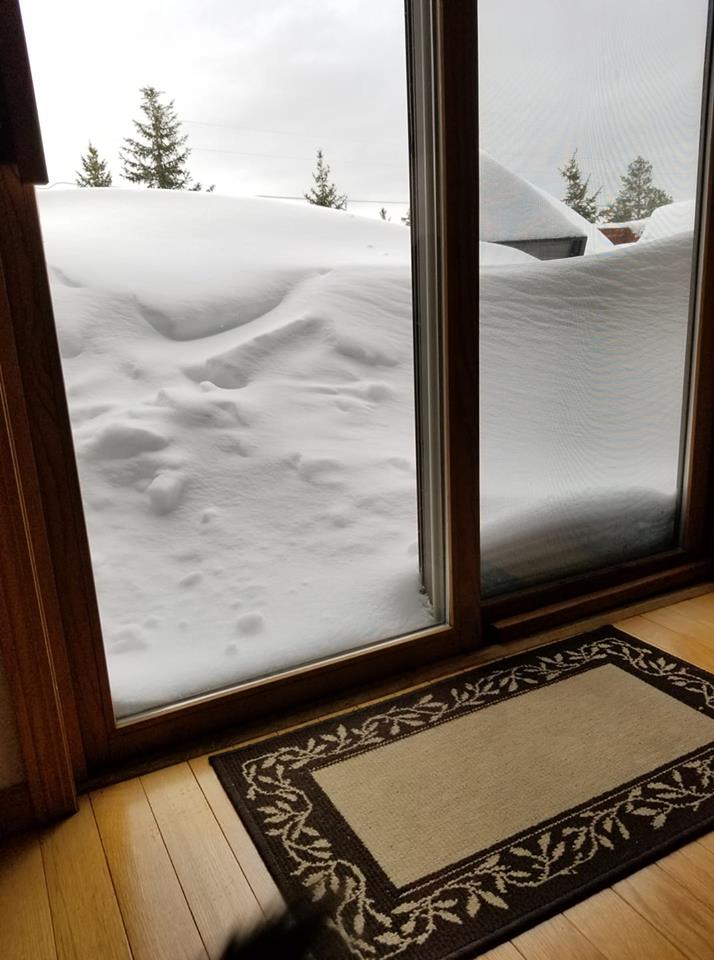 Deep snow piled against the glass door of a home in Boulder Canyon, South Dakota.