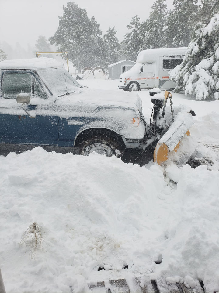 Deep, heavy snow surrounding a pickup truck with plow