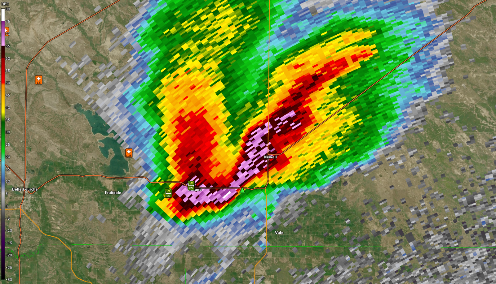 A radar image displays a supercell thunderstorm in vivid colors, with the strongest echoes (reds and purples) extending from Belle Fourche to Newell.